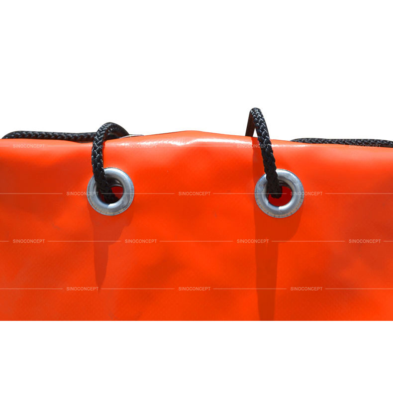 Aluminium eyelets and black strings accessories used on orange PVC sandbags for traffic safety management