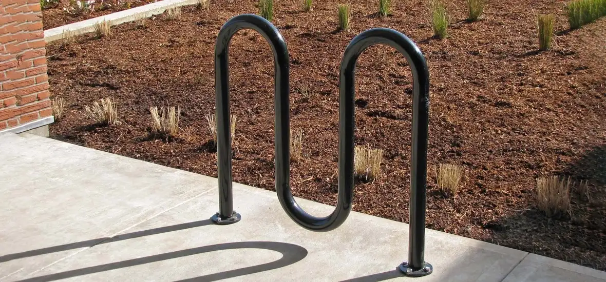 A black wave style bike rack mounted on the ground for bike parking.